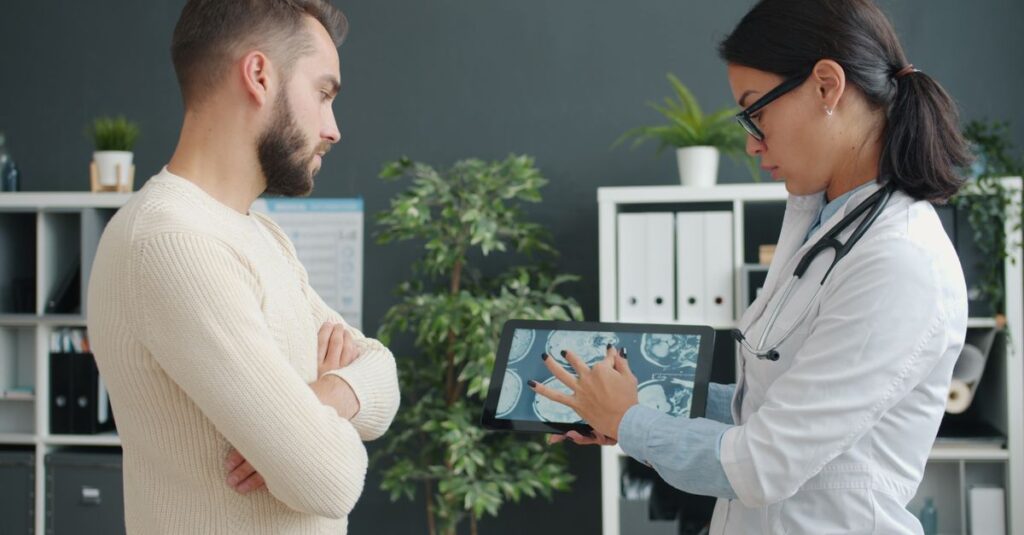 A doctor shows MRI scan to a worried patient using a tablet in a modern clinic. — women with low testosterone symptoms