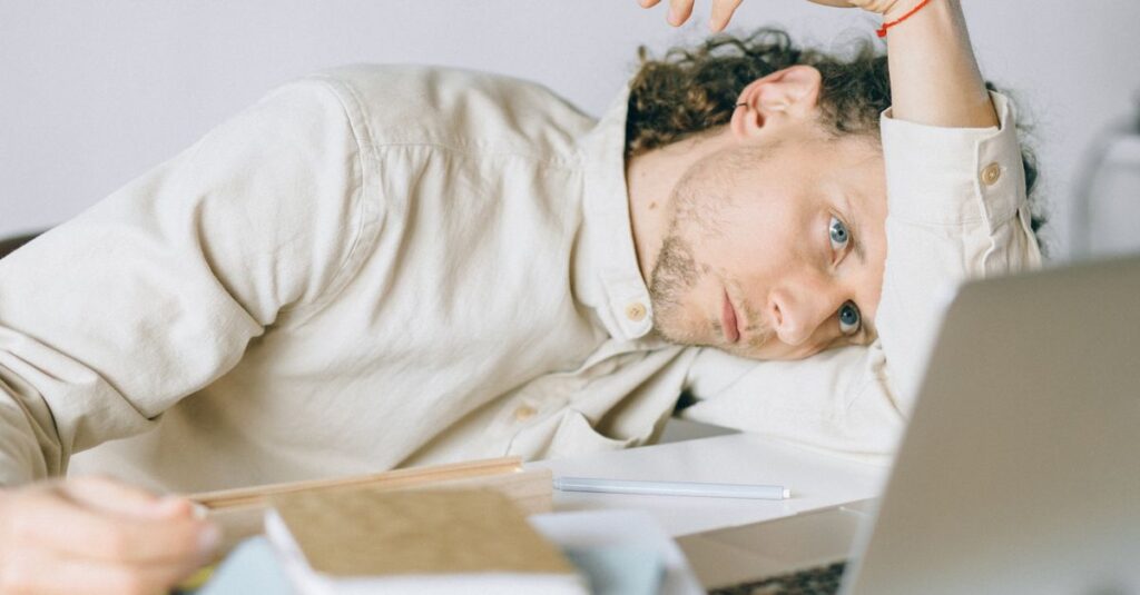 A tired Caucasian man at a desk, showing signs of exhaustion and stress, exemplifying workplace burnout. — low cortisol meme